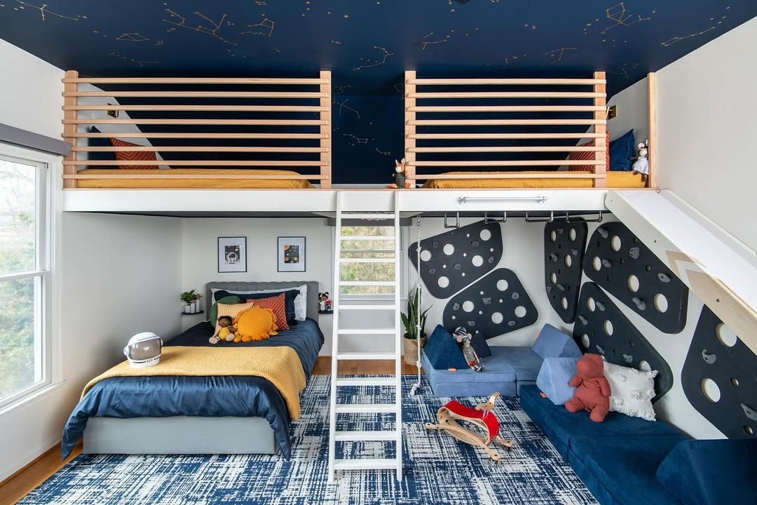 Children’s bedroom with a loft featuring two beds on the upper level, a ladder, smart storage options, a bed and seating area below, space-themed decor, and a constellation ceiling—perfect for inspiring new boys bedroom ideas and restful sleep.