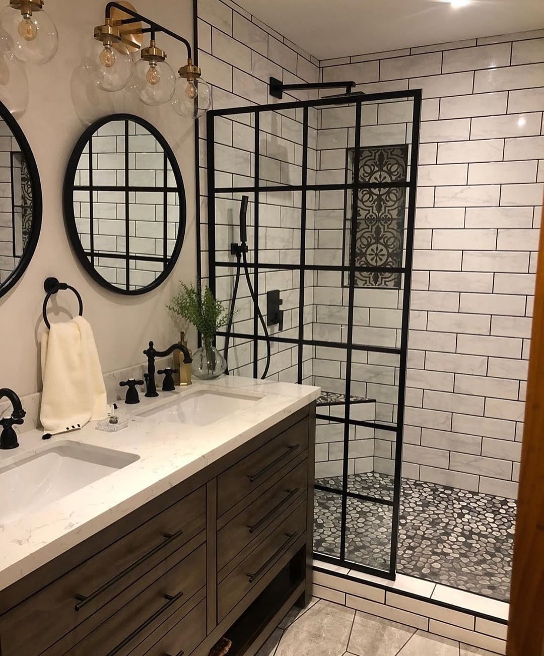 Modern bathroom ideal for small bathrooms, with a walk-in shower featuring a glass enclosure with black grid lines, a double sink vanity with black fixtures, and white subway tile walls.