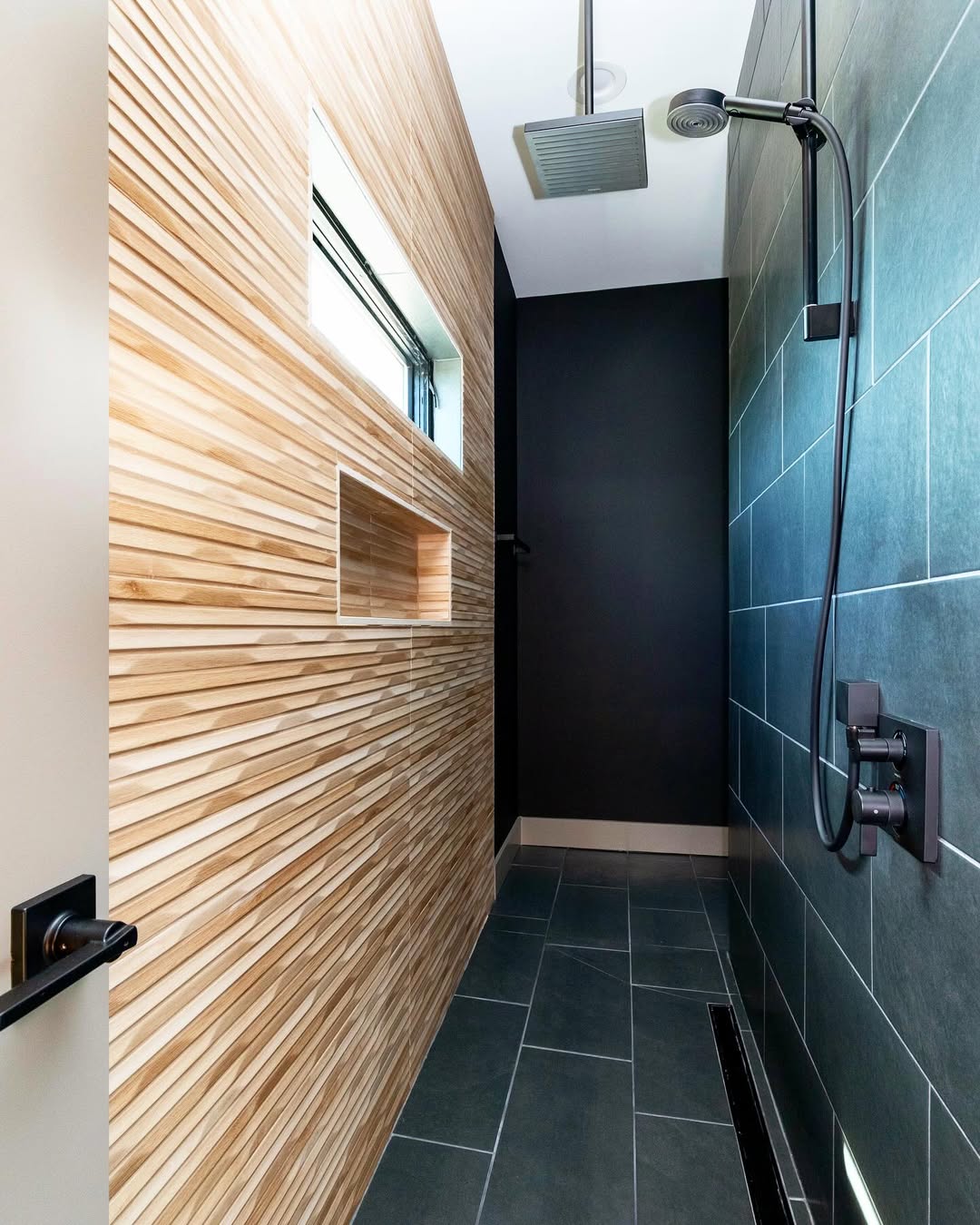 Modern walk-in shower with a black tiled wall, rainfall showerhead, matte black fixtures, and a textured wooden accent wall—perfect inspiration for walk-in shower ideas in small bathrooms or stylish no door showers.