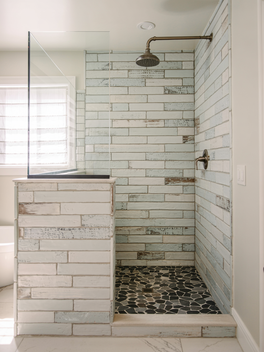 Discover inspiring walk-in shower ideas with a no door walk-in shower, featuring rustic white and blue subway tiles and a pebble stone floor—perfect for small bathroom ideas.