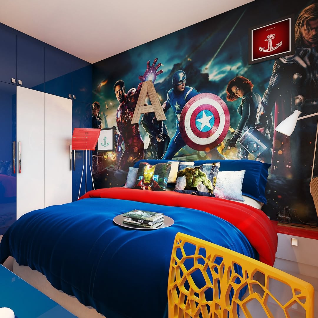 A boys bedroom idea featuring a blue and red bedspread, superhero-themed pillows, and an Avengers mural behind the bed, with clever storage solutions to keep the space tidy for any Marvel fan.