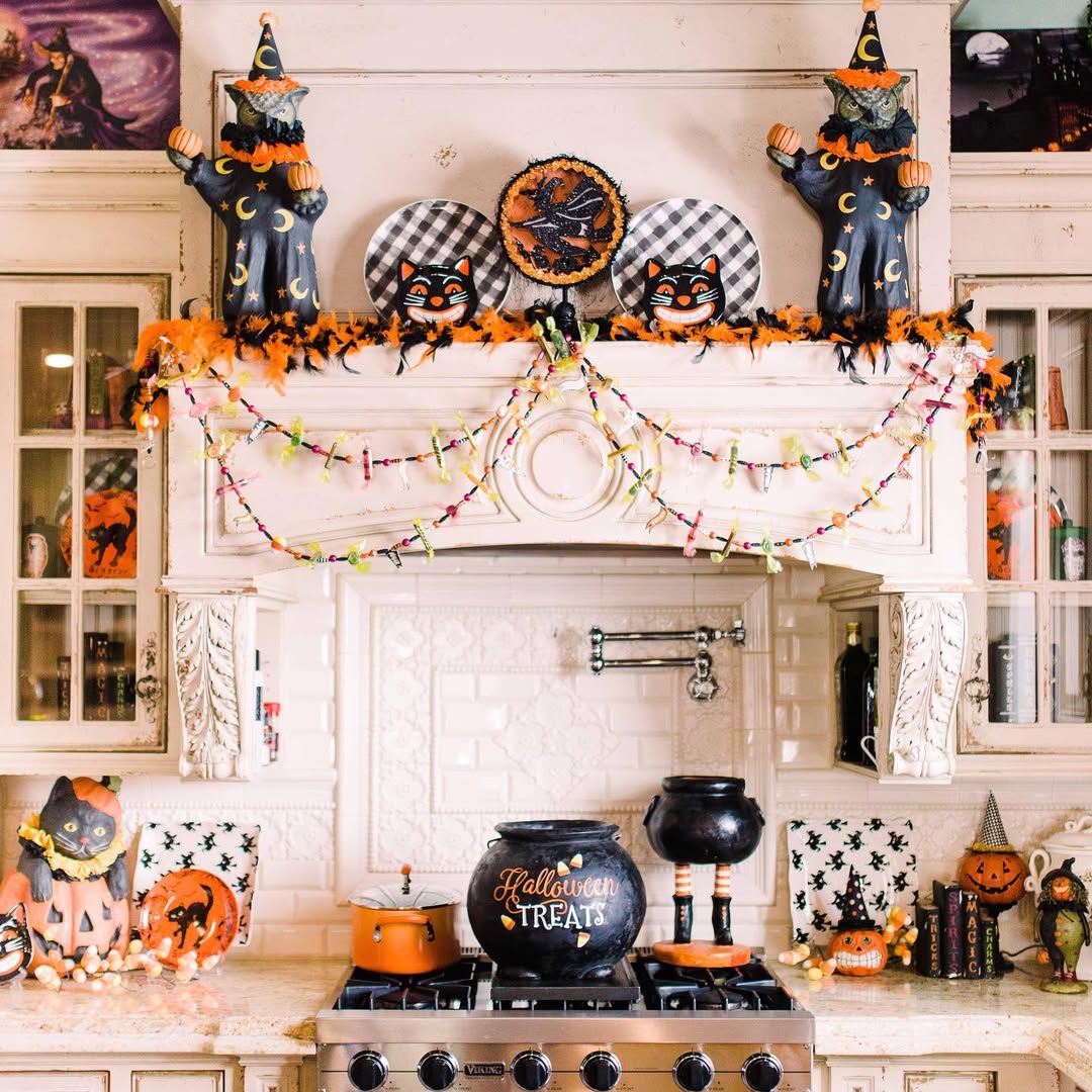 A kitchen decorated for Halloween 2025 with witch and cat figurines, garlands, pumpkins, and a cauldron labeled