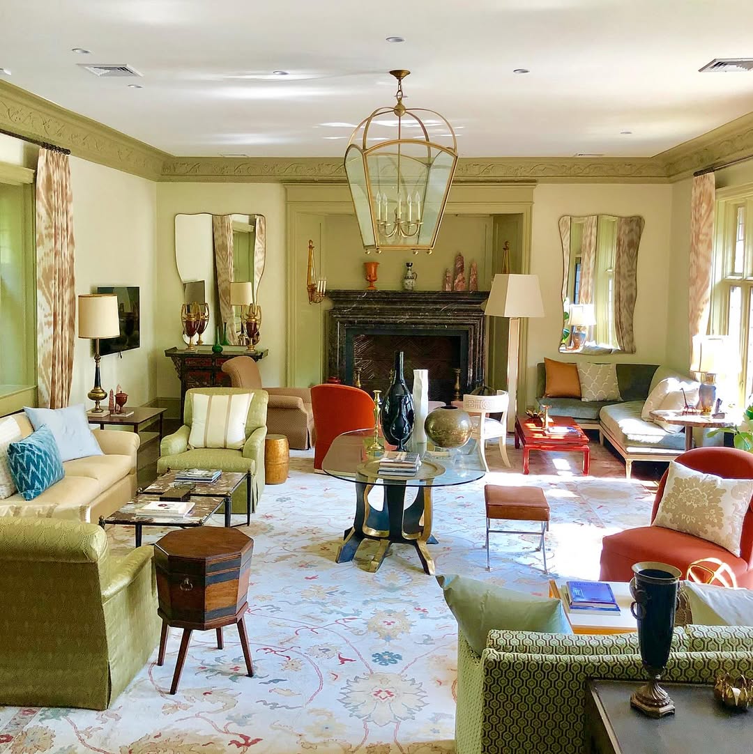 A spacious, well-lit living room with eclectic furniture, a glass table, decorative rugs, a fireplace, and large windows letting in natural light—perfect for those seeking relaxed Island Living Room Ideas.