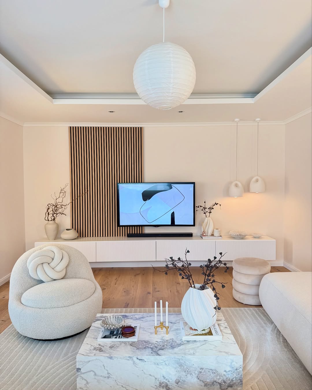 Modern Living Room with neutral tones, marble coffee table, abstract decor, and a TV mounted on a white console under a wood slat feature—perfect inspiration for your own 30 living room design.