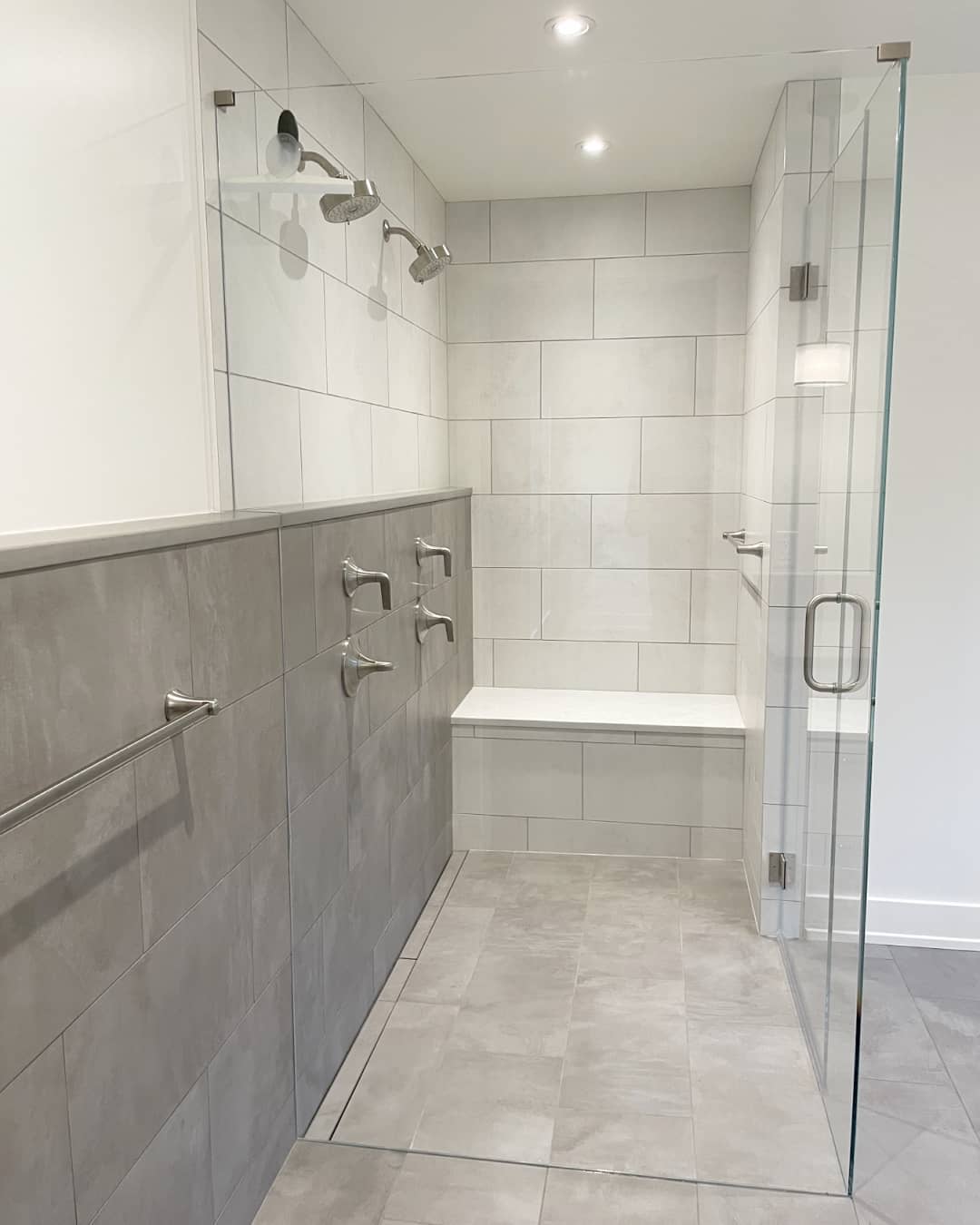 Modern walk-in shower perfect for small bathrooms, featuring gray tile, glass door, dual showerheads, built-in bench, and stainless steel grab bars and towel rack—an inspiring choice for walk-in shower ideas.