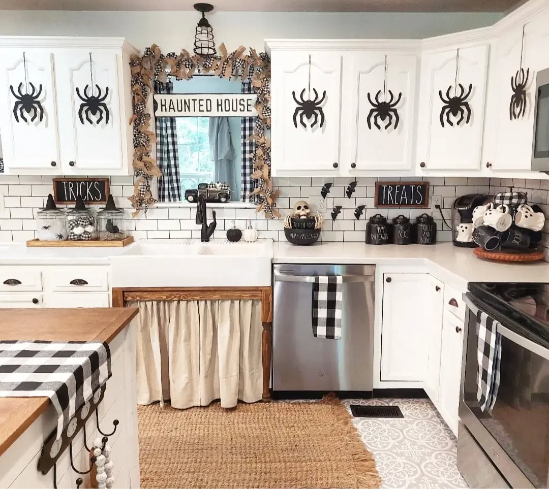 A kitchen decorated for Halloween 2025 features black spider cutouts on white cabinets, a