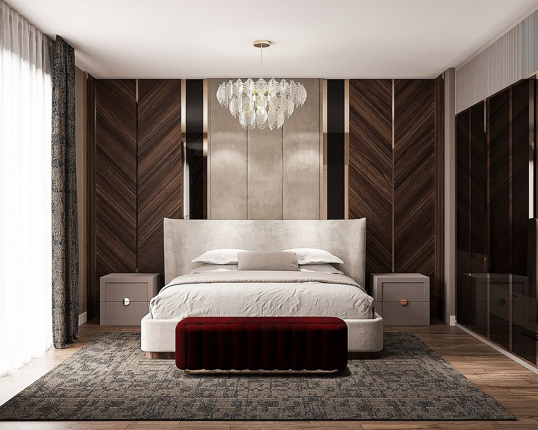 Modern Italian bedroom featuring a large bed, gray bedding, two nightstands, a red upholstered bench, wood panel walls, a chandelier, and floor-to-ceiling windows with elegant curtains.