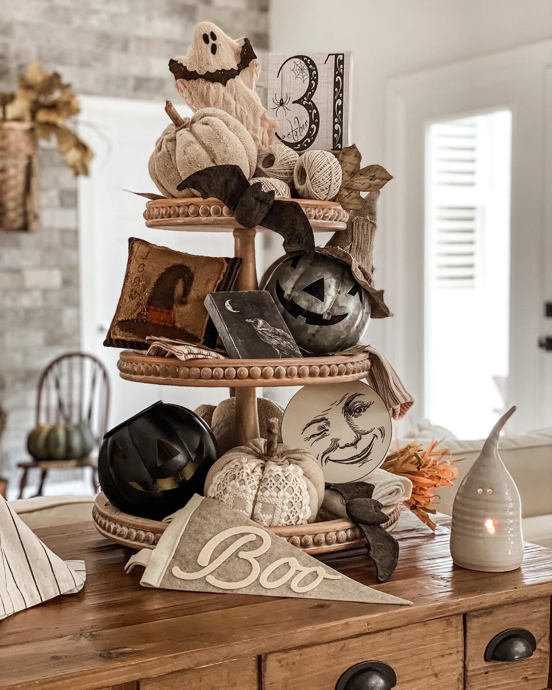 A two-tiered wooden tray decorated with pumpkins, Halloween-themed signs, and a “Boo” pennant offers festive Halloween kitchen decor inspiration in a cozy, neutral-toned room. Perfect for fresh Halloween decor ideas for your kitchen in 2025.