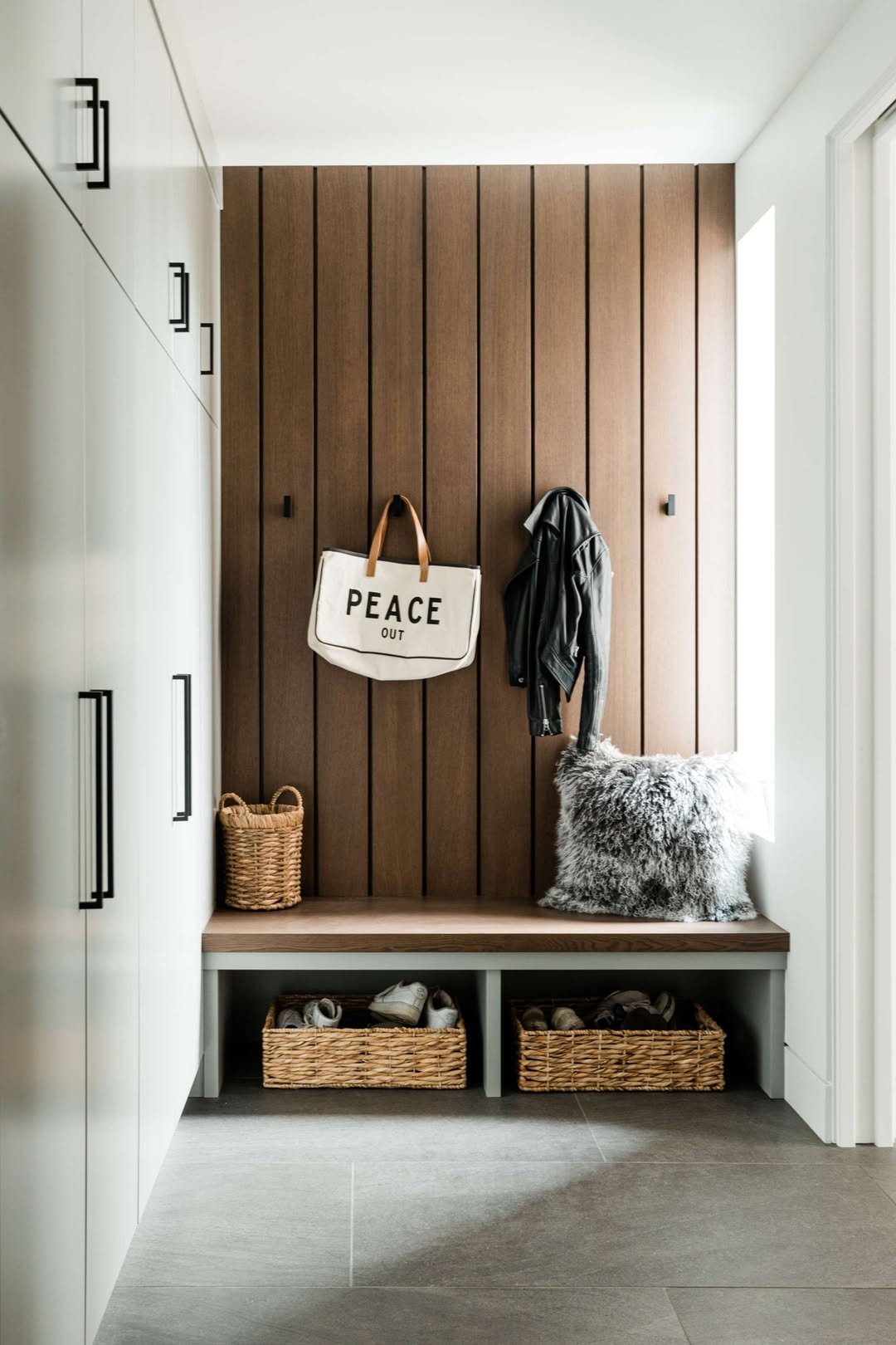 A genius mudroom featuring a wood accent wall, bench, storage baskets, a